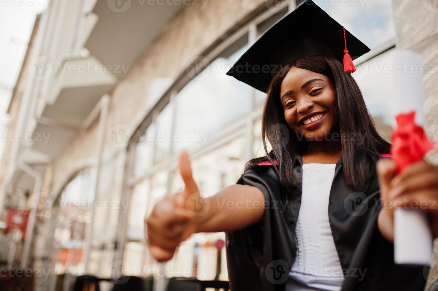 jonge vrouwelijke Afro-Amerikaanse student met diploma poseert buitenshuis. foto