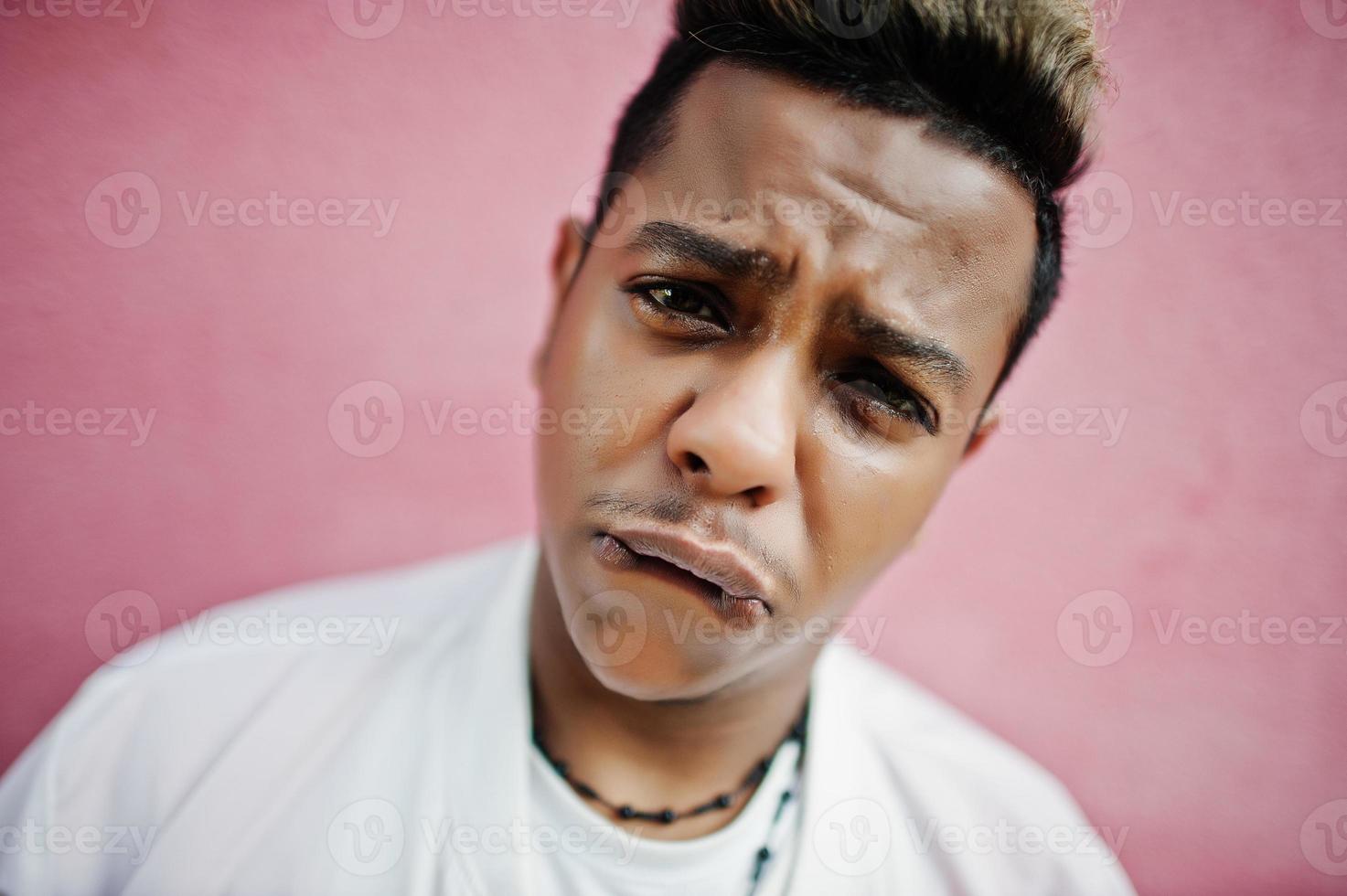 close-up gezicht van stijlvolle hipster Arabische man man poseerde buiten in de straat. stijl rapzanger tegen roze muur. foto