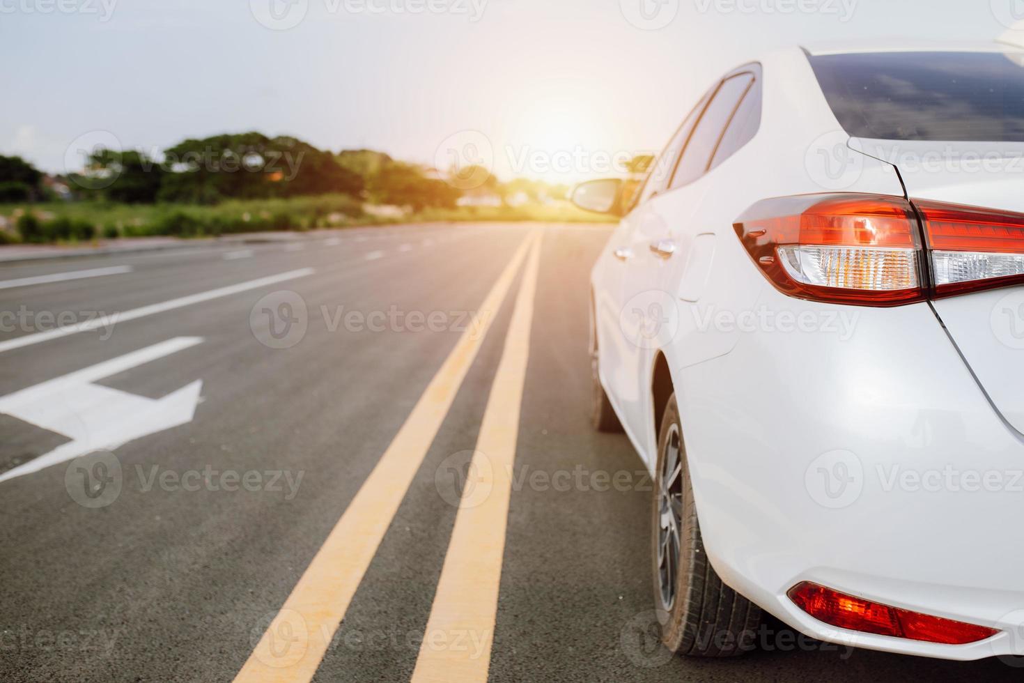 close-up van witte auto op een schilderachtige weg met zonsondergang, auto op de weg omringd door natuurlijk landschap, concept voor reizen in vakantie. foto