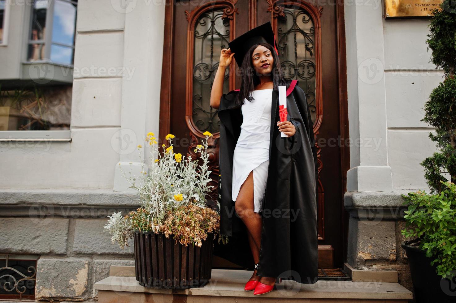 jonge vrouwelijke Afro-Amerikaanse student met diploma poseert buitenshuis. foto