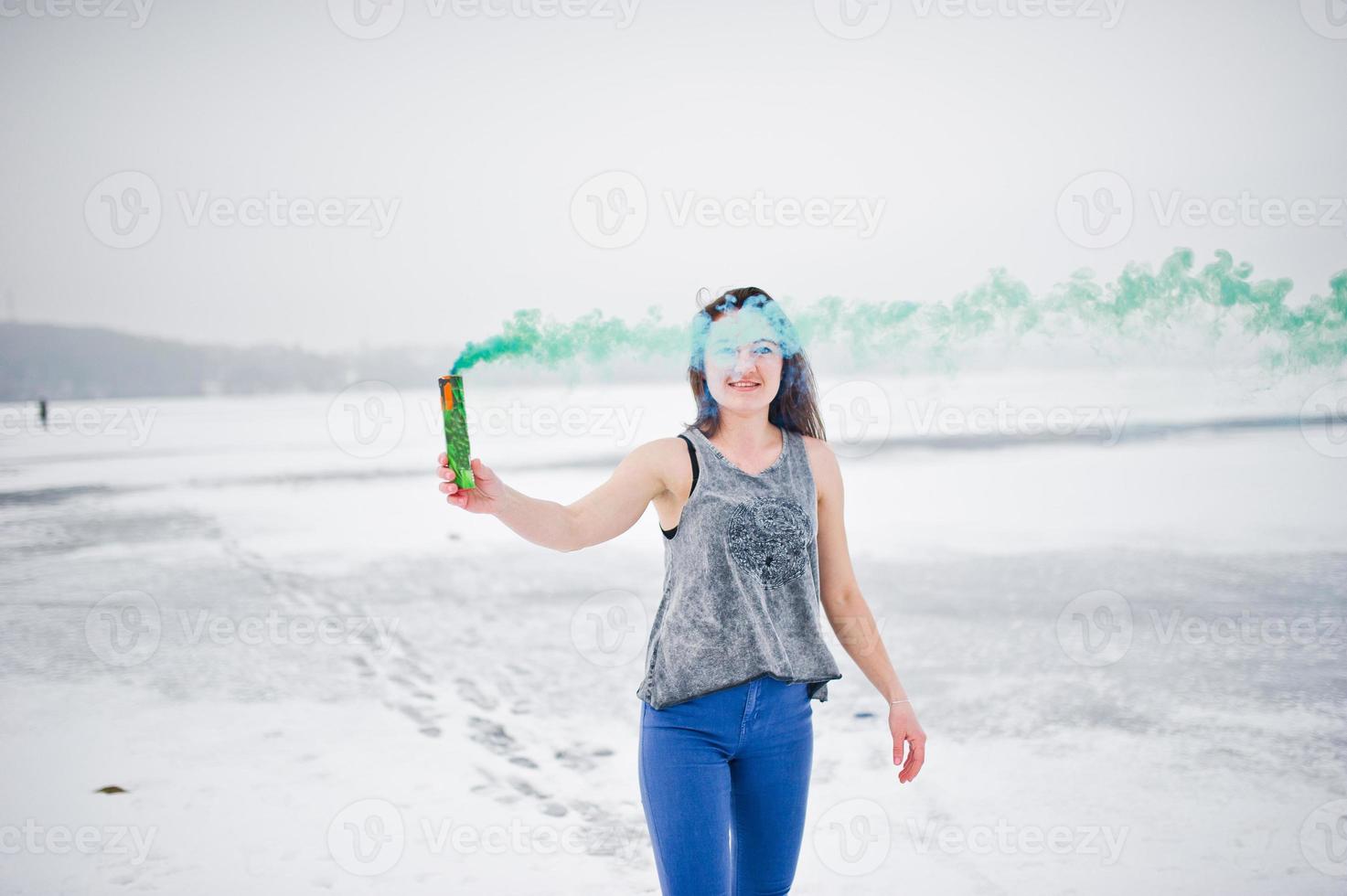 jong meisje met groen gekleurde rookbom in de hand in de winterdag. foto