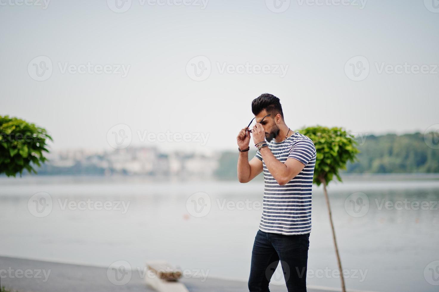 knappe lange Arabische baard man model op gestript shirt buiten geposeerd. modieuze Arabische man bij zonnebril. foto