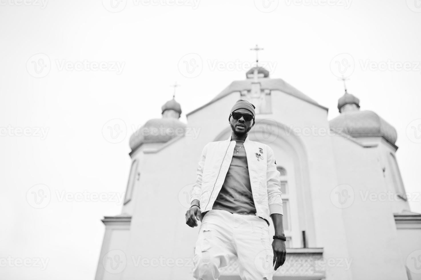 Afro-Amerikaanse man in hoed en zonnebril staan tegen de kerk. geloof en christendom in afrika. foto