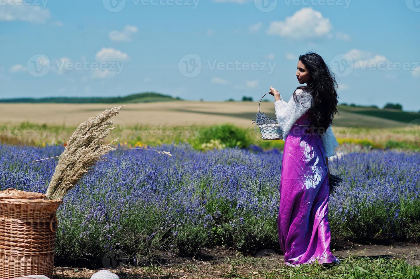 mooi indiaans meisje draagt saree india traditionele kleding in paarse lavendelveld met mand. foto