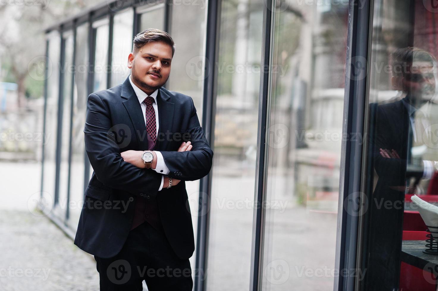 stijlvolle Indiase zakenman in formele kleding die tegen ramen staat in het zakencentrum. foto