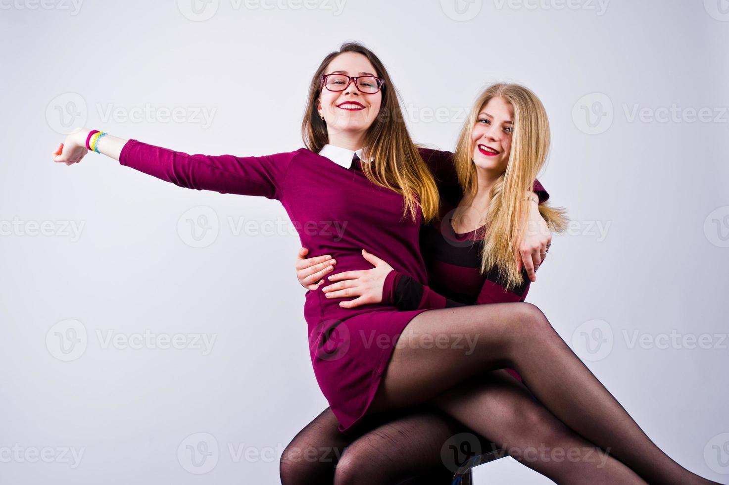 meisjes in paarse jurken die plezier hebben en poseren op de stoel in de studio. foto