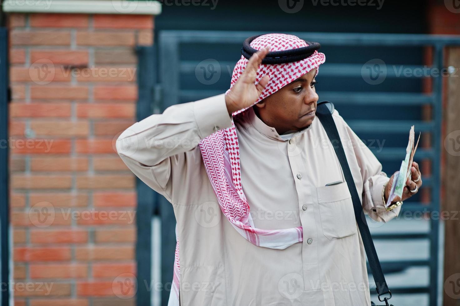Midden-Oosten Arabische zakenman poseerde op straat tegen modern gebouw met zwarte handtas en eurogeld. foto
