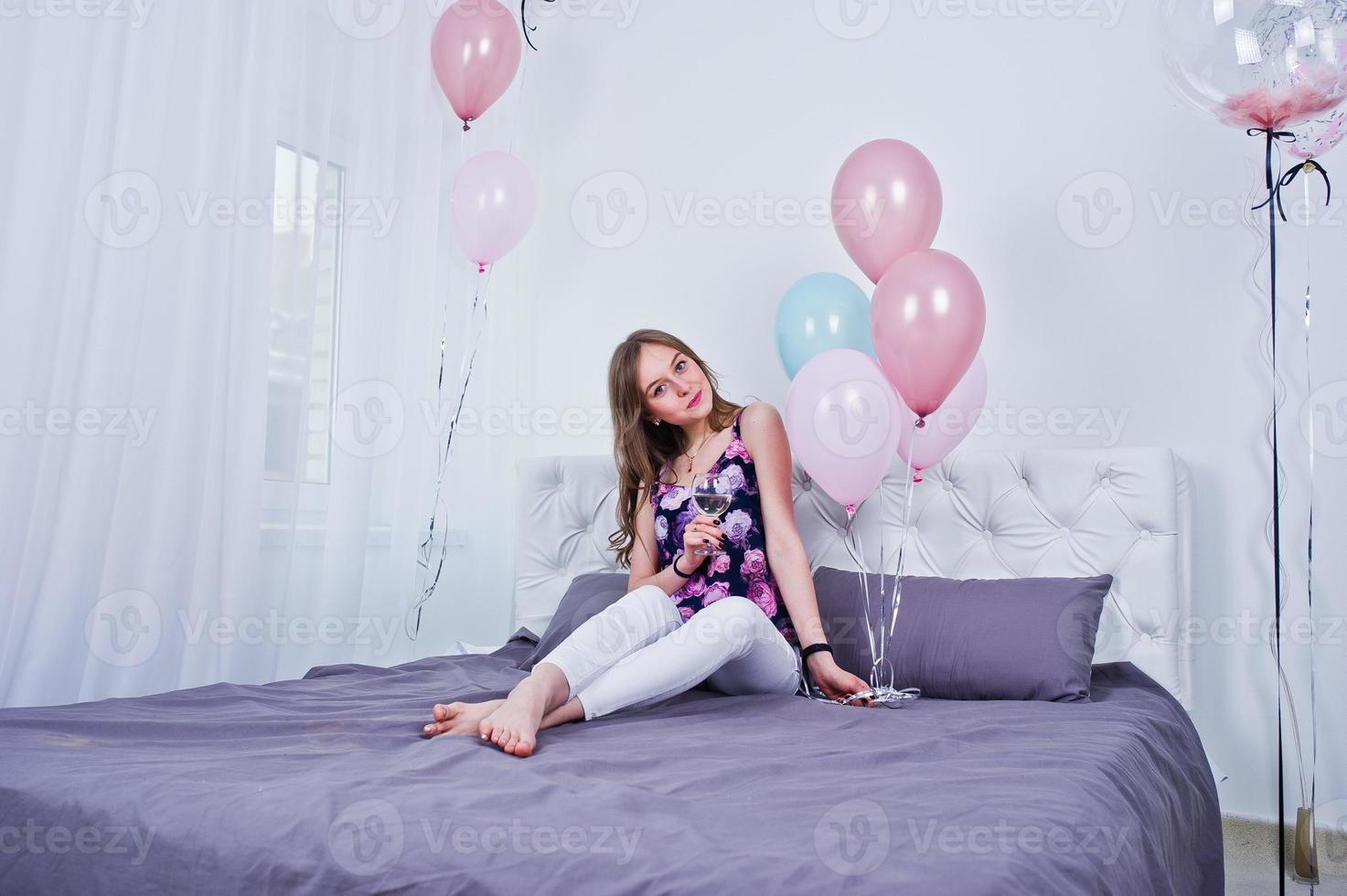 gelukkig meisje met gekleurde ballonnen op bed op kamer. verjaardag thema vieren. foto