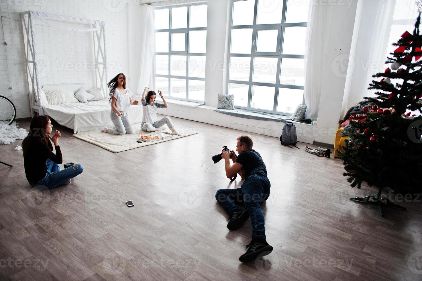 het team van twee fotografen die foto's maken van studio-tweelingmeisjes die pizza eten. professionele fotograaf op het werk. foto