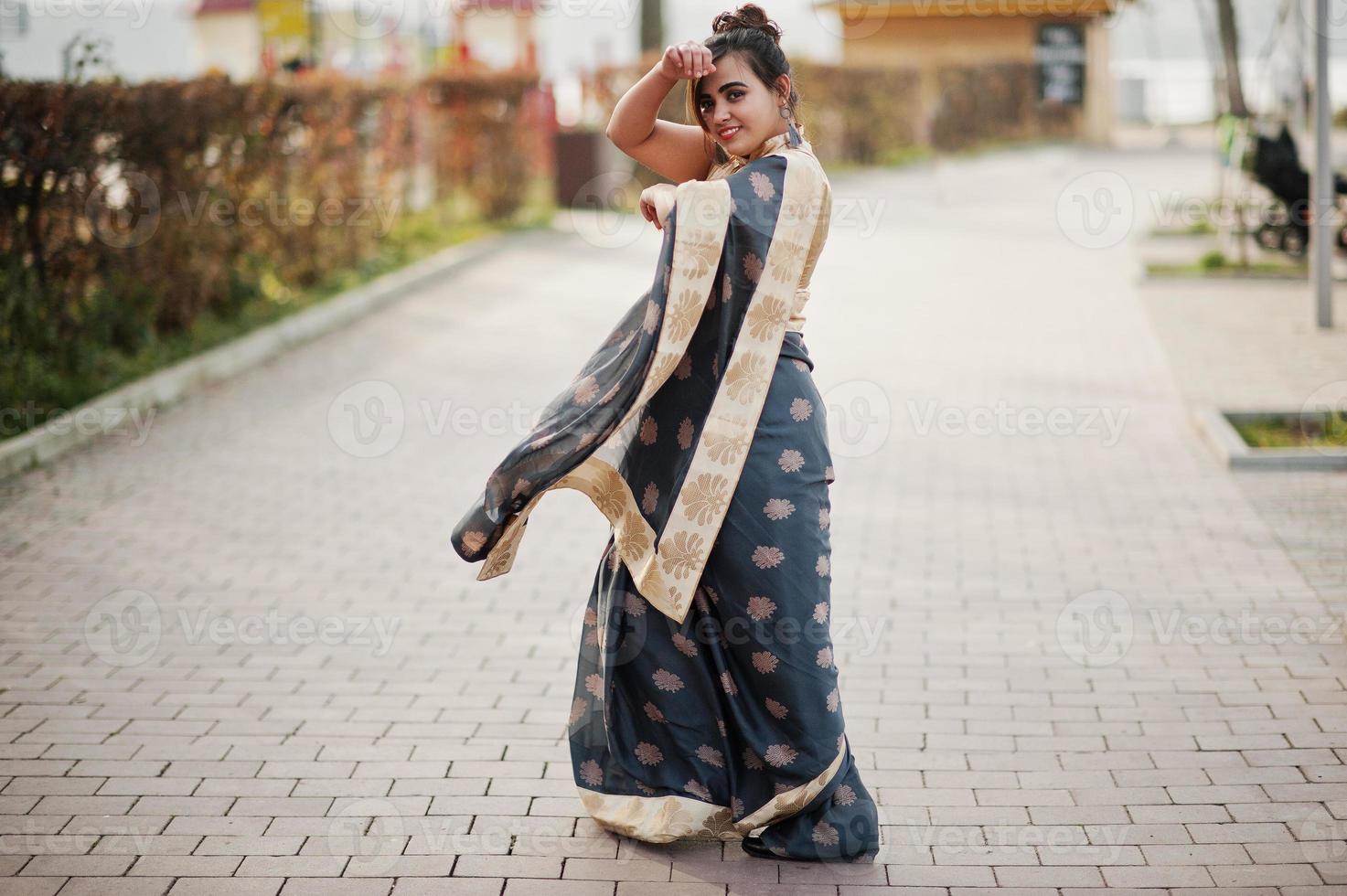 elegante brunette Zuid-Aziatische Indiase meisje in saree dansen buiten. foto