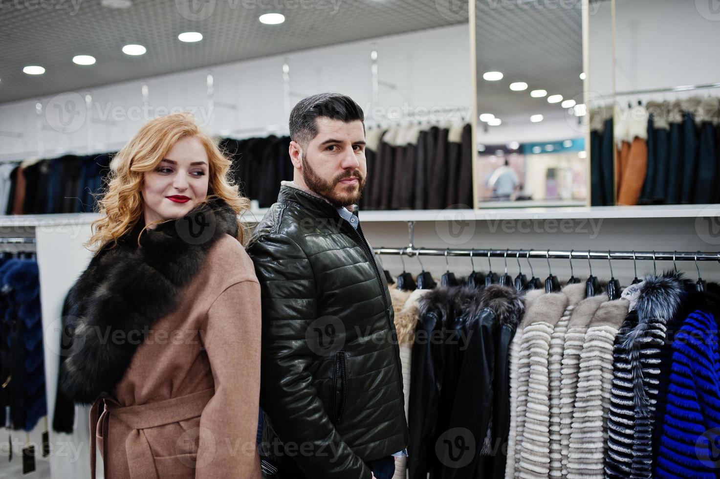 elegantie blond meisje in bontjas en stijlvolle turkse man in de winkel van bontjassen en leren jassen. foto