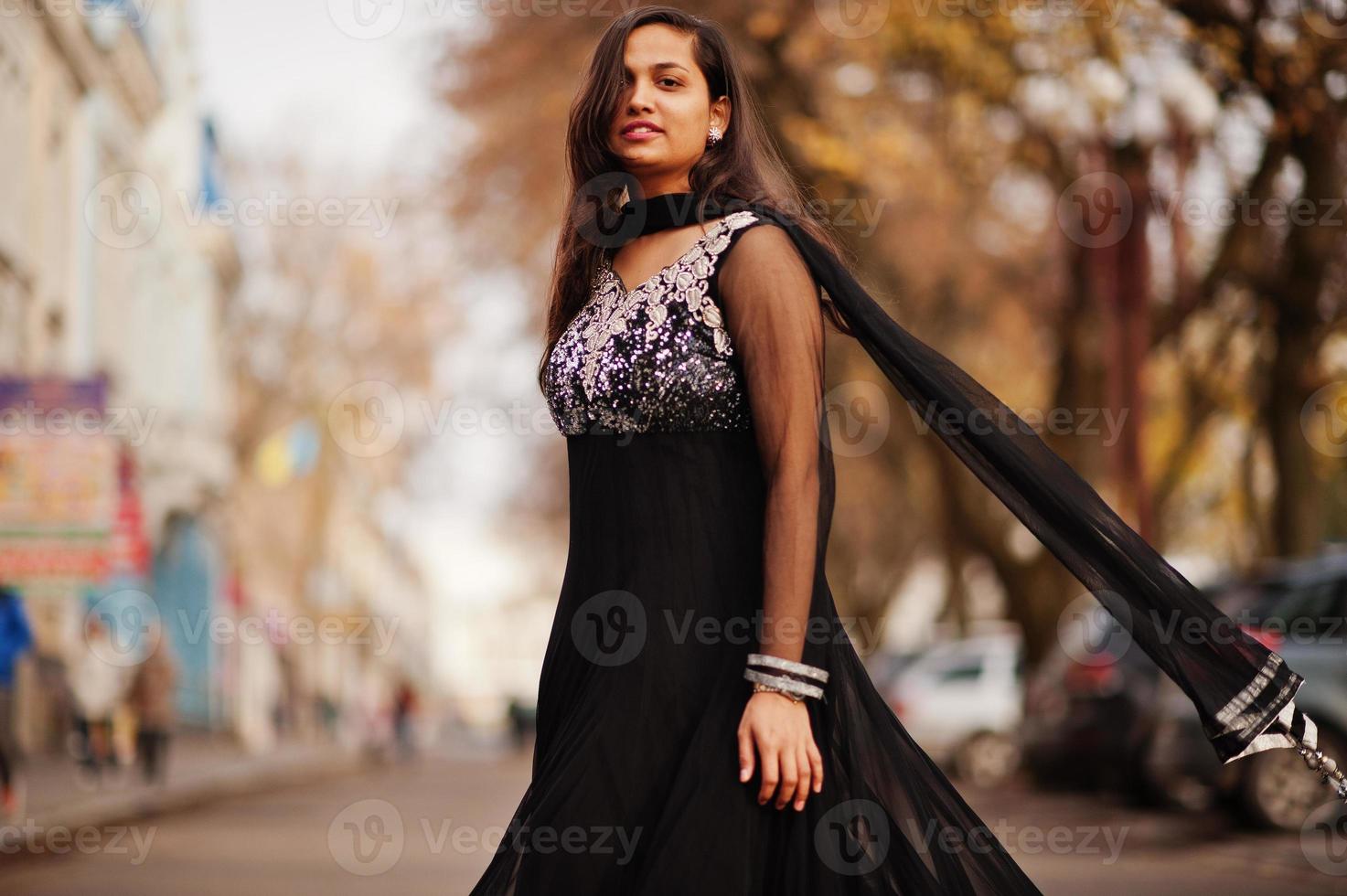 vrij indisch meisje in zwarte saree-jurk poseerde buiten in de herfststraat. foto