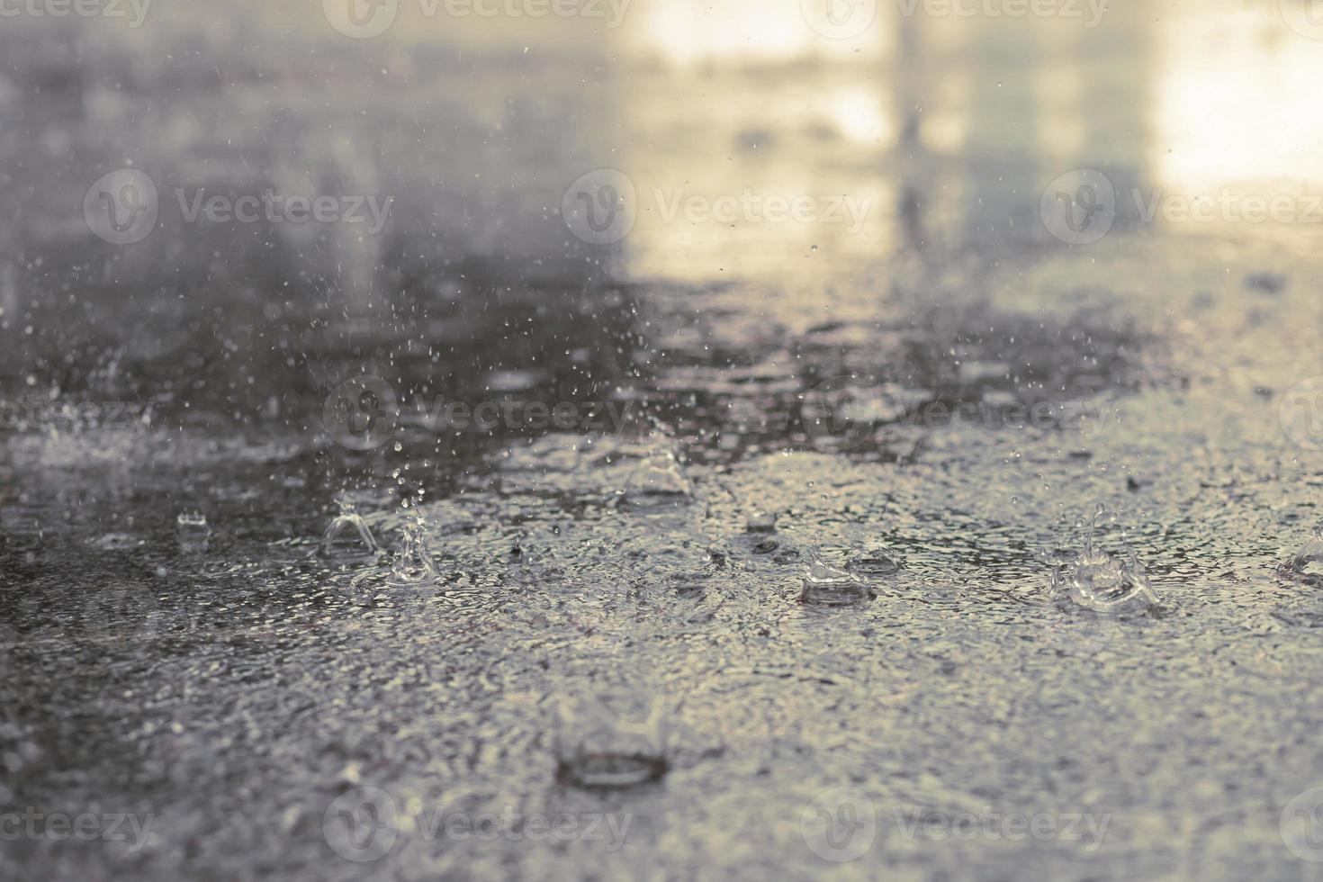 regendruppels in het water zwaar op asfalt schaduw van zwarte schaduw en reflectie van donkere lucht in de stad. hoog contrast in de herfst foto