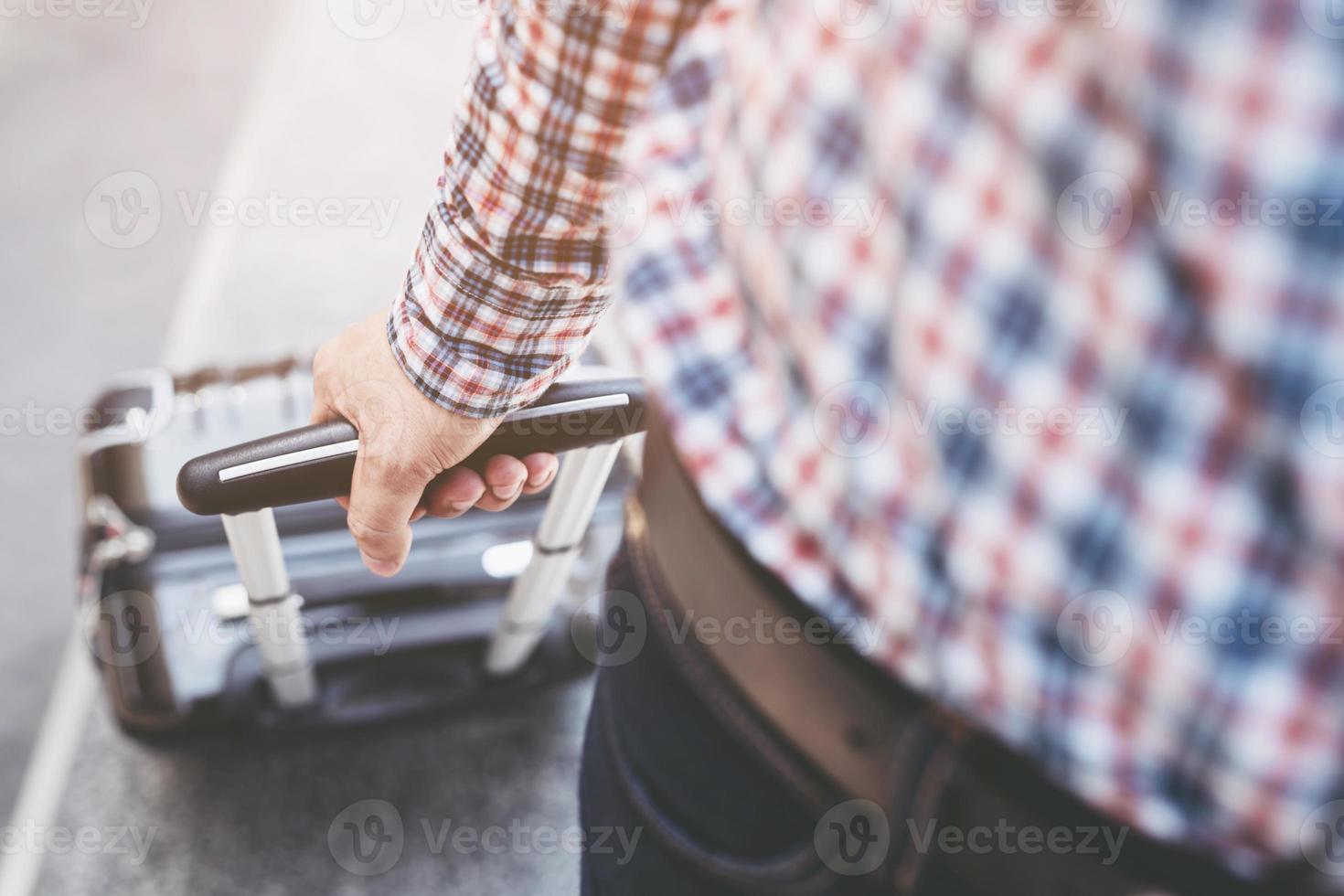 jonge man trekt koffer in luchthaventerminal foto