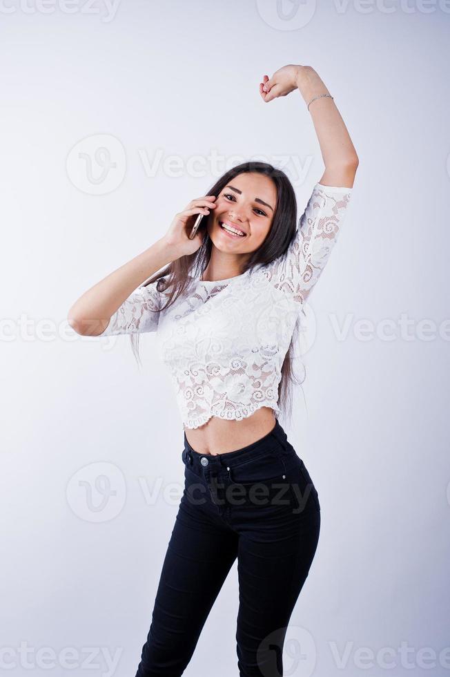 portret van een jonge mooie vrouw in witte top en zwarte broek met behulp van haar telefoon. foto