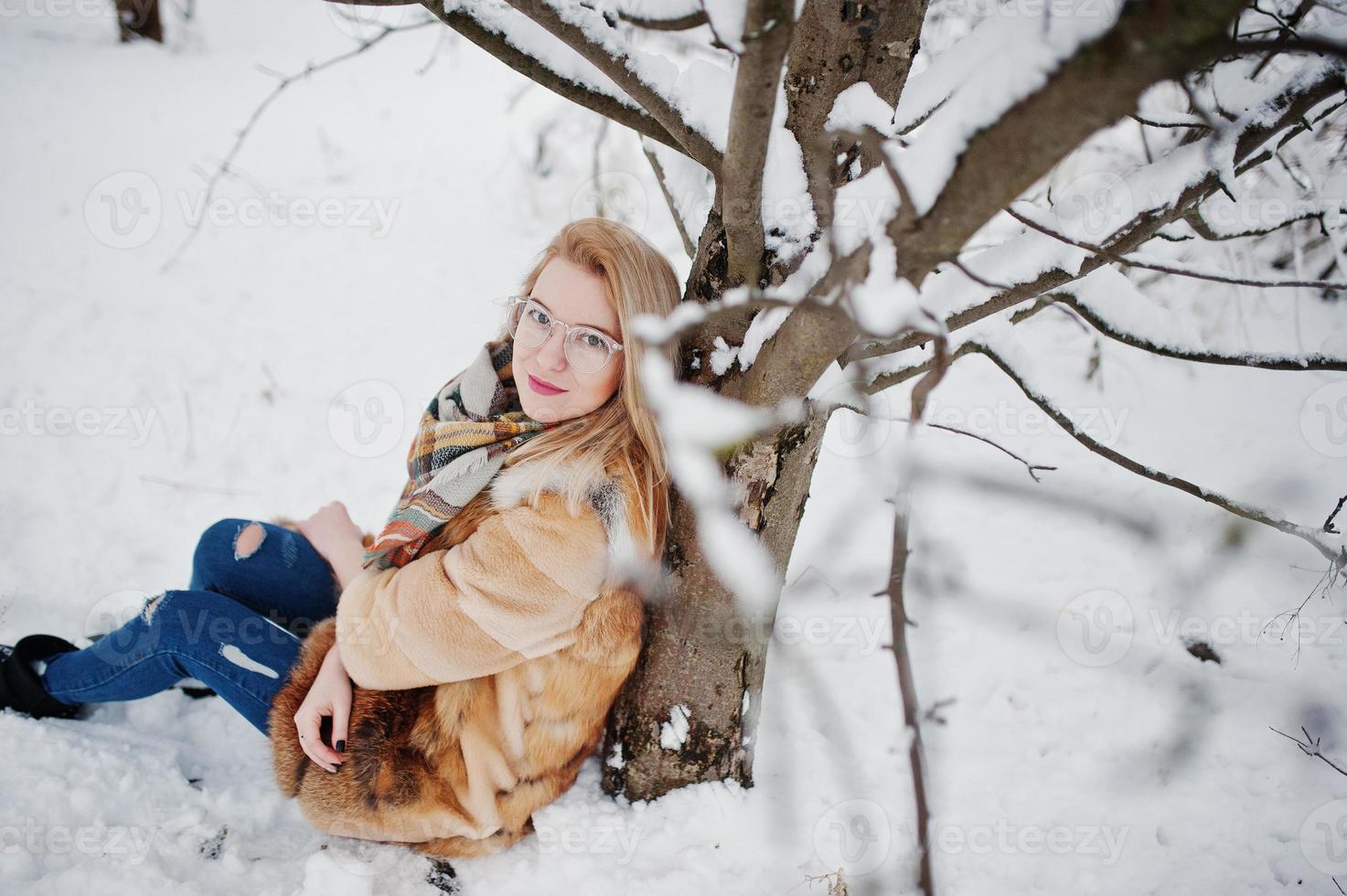 portret van blond meisje in glazen, rode bontjas en sjaal op winterdag. foto