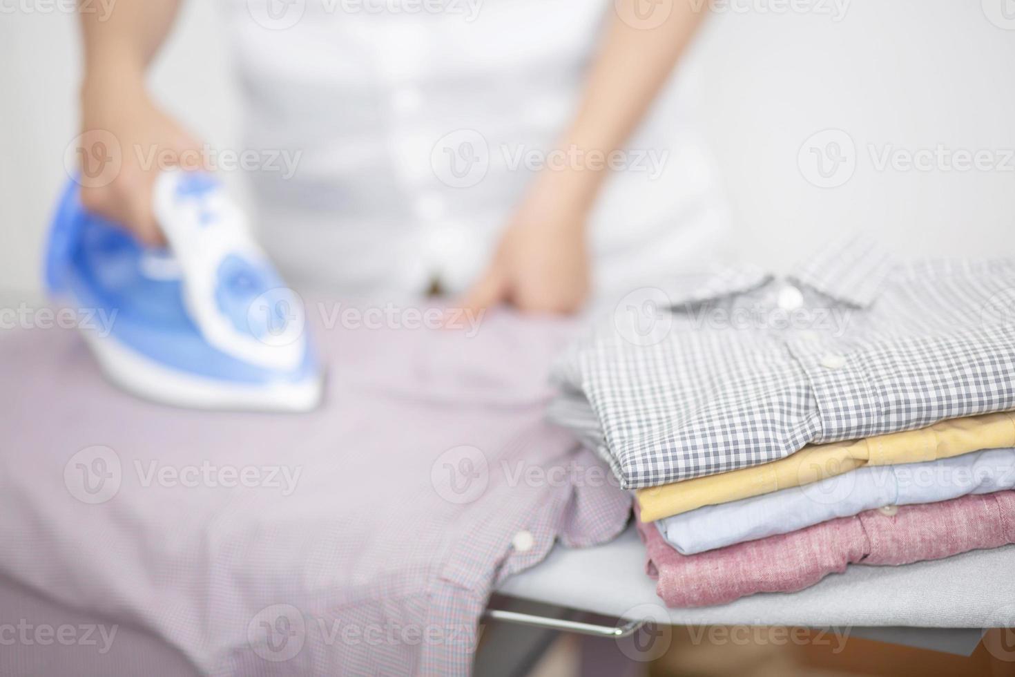 strijkijzer en stapel schone kleren shirts verschillende kleuren op strijkplank. laat ruimte om zijtekst te schrijven. foto