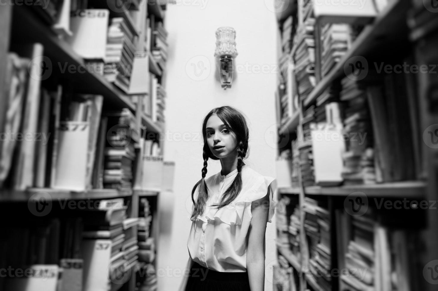 meisje met staartjes in witte blouse bij oude bibliotheek. foto