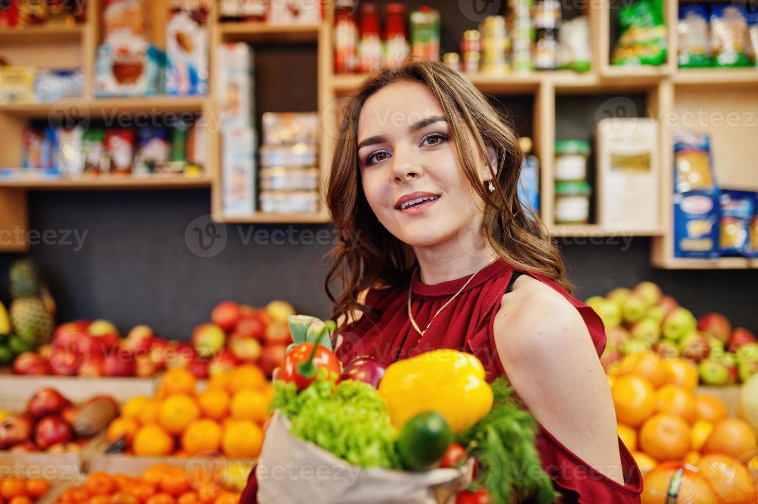 meisje in het rood met verschillende groenten in de fruitwinkel. foto