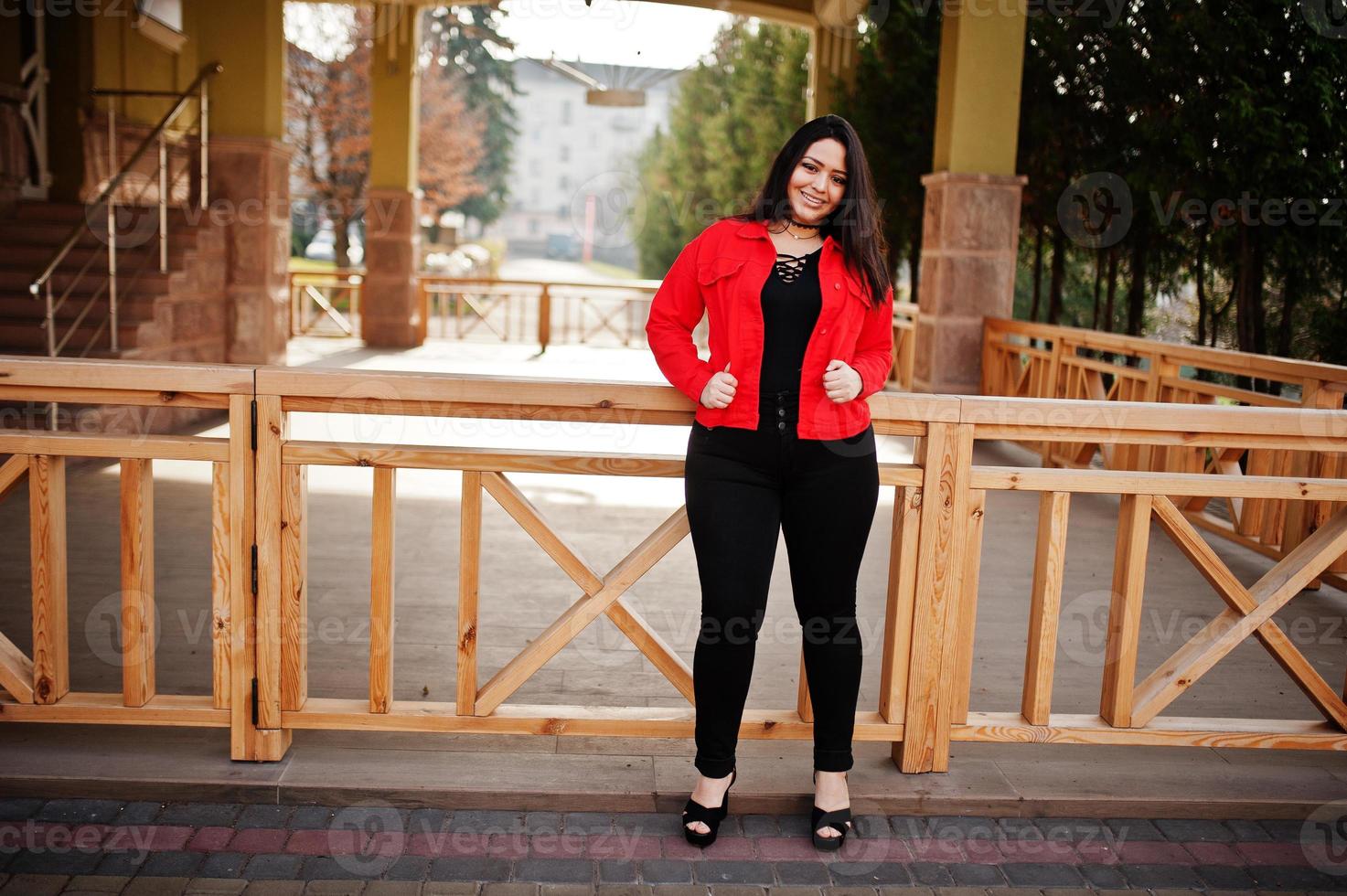 mooie latino model meisje uit ecuador slijtage op zwarte en rode jas gesteld op straat. foto