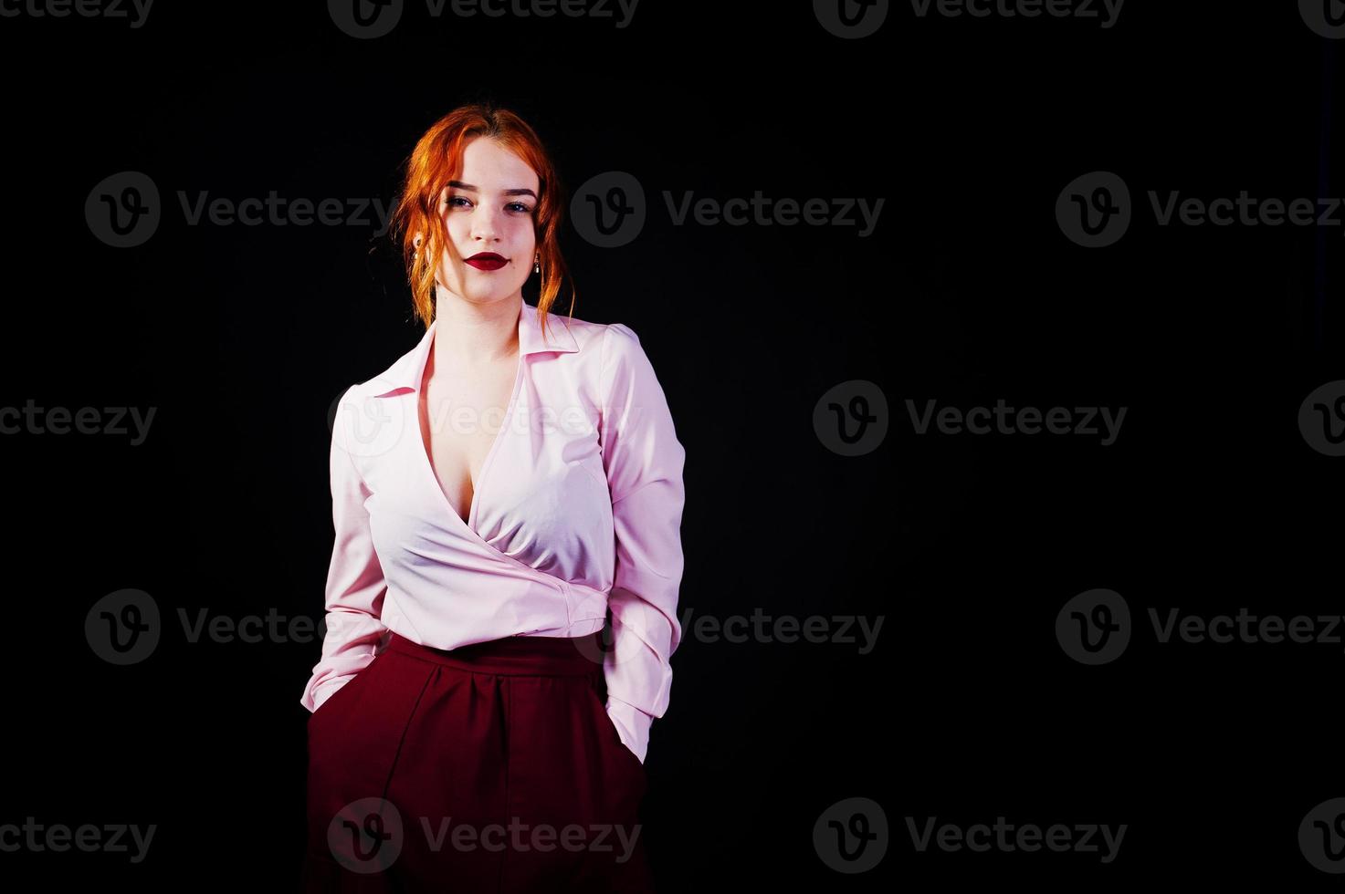 portret van een roodharige meisje in roze blouse en marsala rok op de zwarte achtergrond. foto