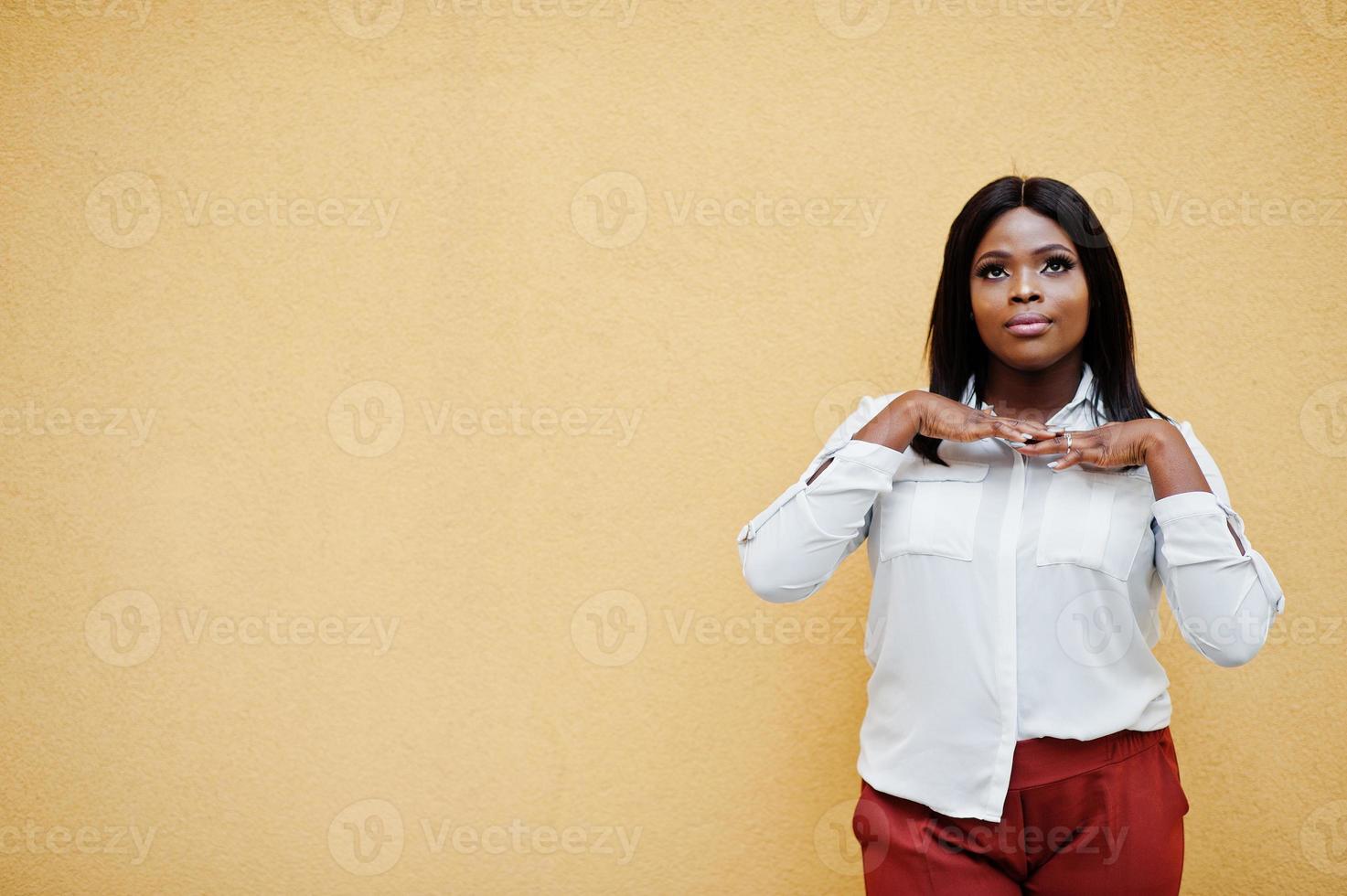 formeel geklede Afro-Amerikaanse zakenvrouw in witte blouse en rode broek geïsoleerd op gele achtergrond. succesvolle zakenvrouw met een donkere huid. foto