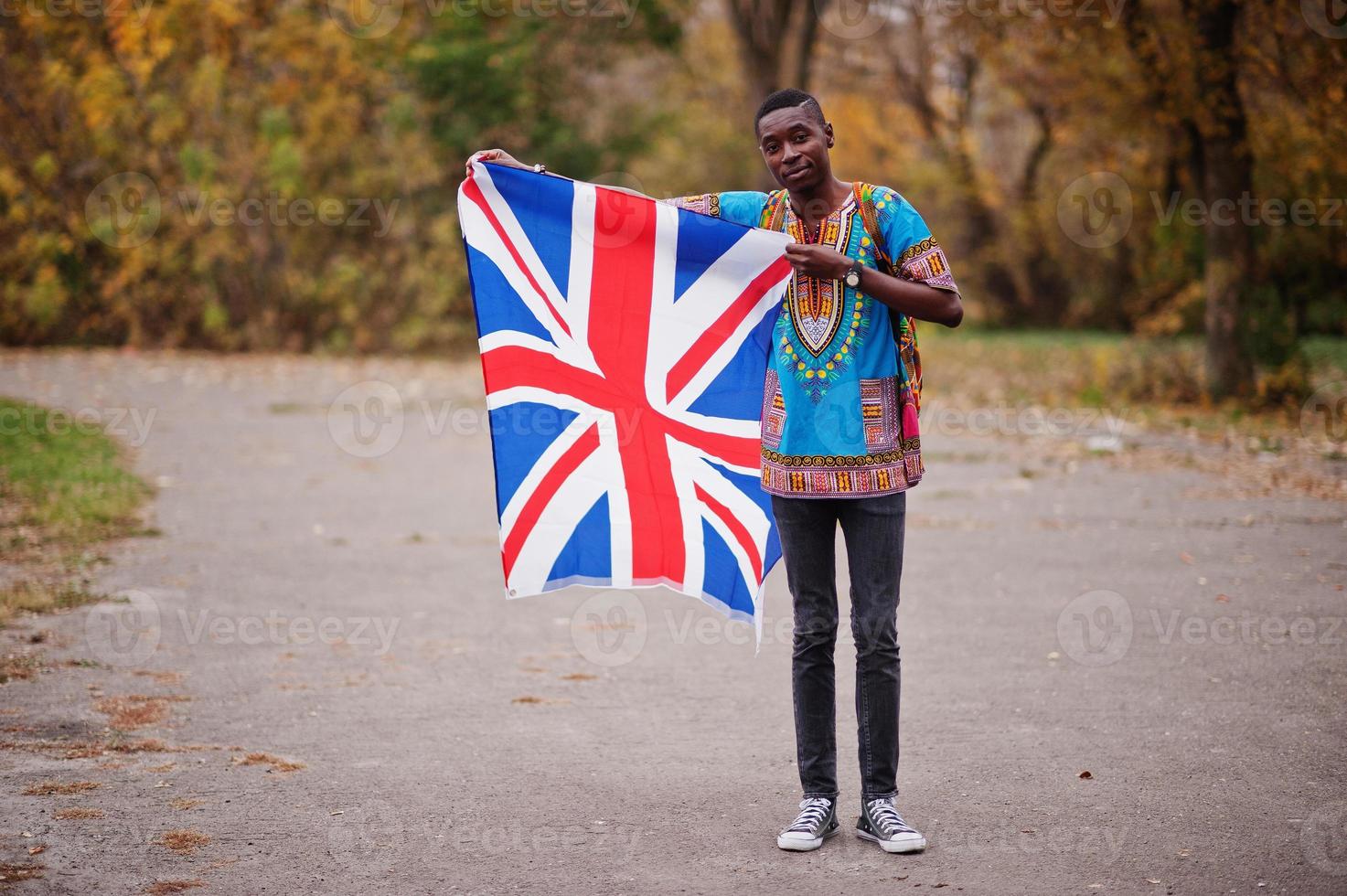 afrikaanse man in afrika traditioneel shirt op herfstpark met de vlag van groot-brittannië. foto