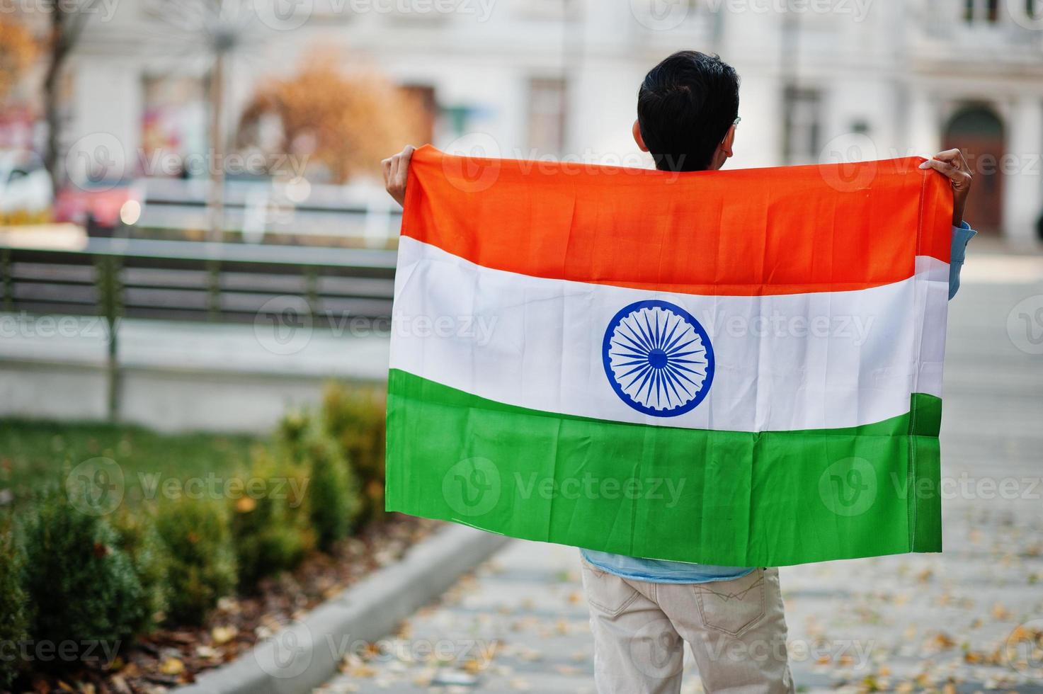 Zuid-Aziatische Indiase mannelijke student met de vlag van india buiten geposeerd. foto