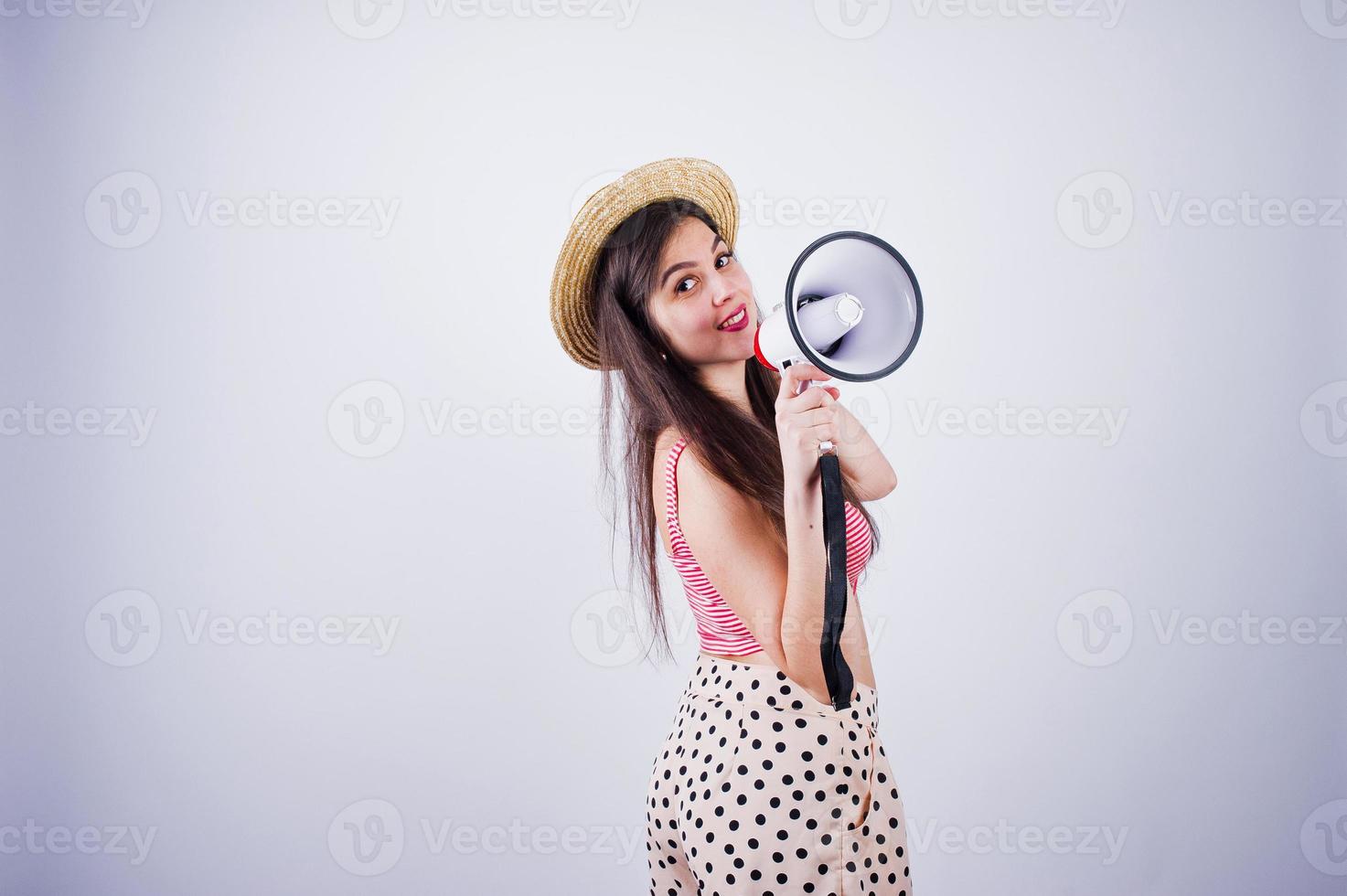 portret van een prachtig jong meisje in zwempak en hoed praat in megafoon in de studio. foto