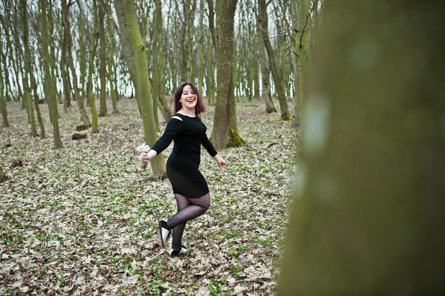 portret van brunette meisje in zwarte jurk op lente hout. foto