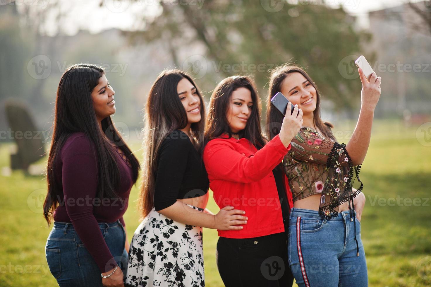 groep van vier gelukkige en mooie latino-meisjes uit ecuador poseerden op straat en maakten selfie op de telefoon. foto