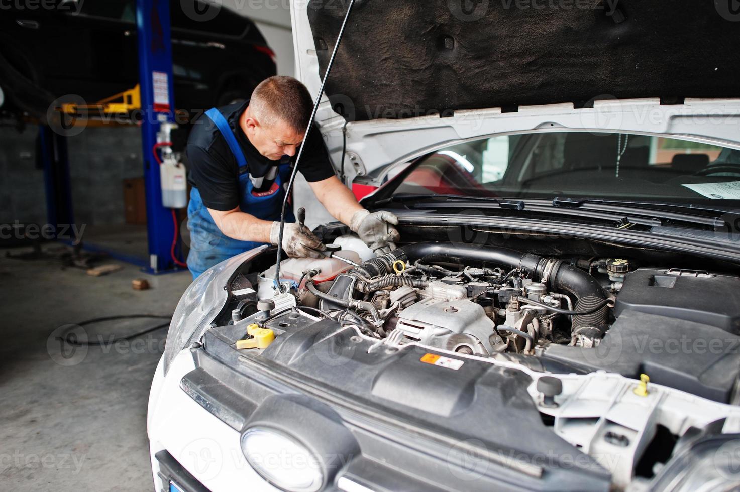 auto reparatie en onderhoud thema. monteur in uniform werken in autoservice, motor controleren. foto