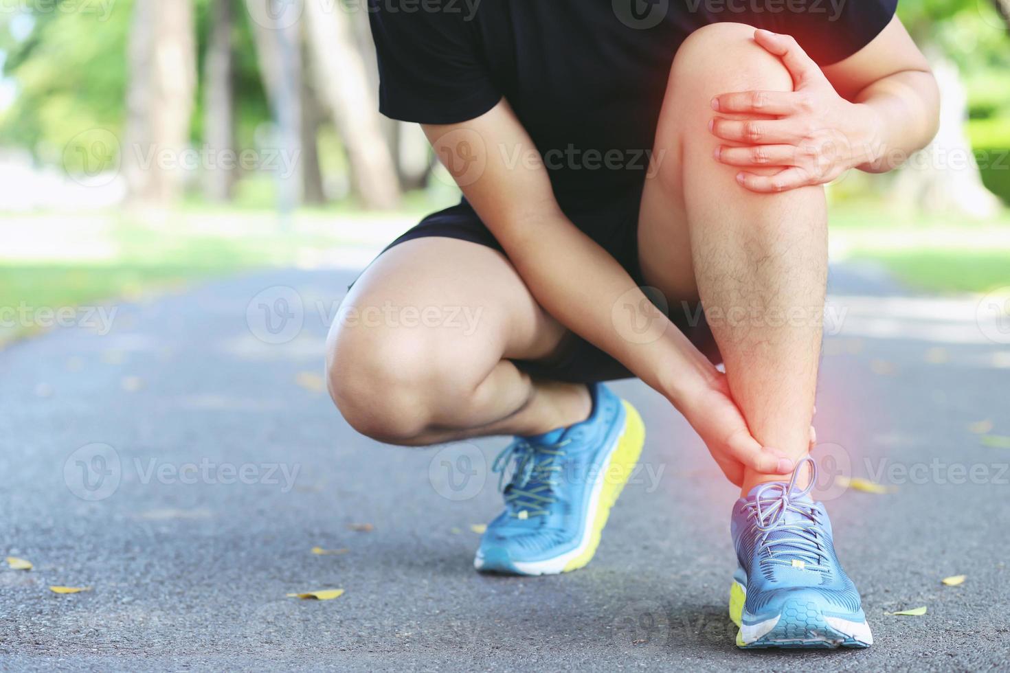 hardloper die pijnlijke gedraaide of gebroken enkel aanraakt. atleet runner training ongeval. sport running enkel verstuikte verstuiking veroorzaken letsel knie. en pijn met beenbotten. focus rode benen op om pijn te tonen. foto