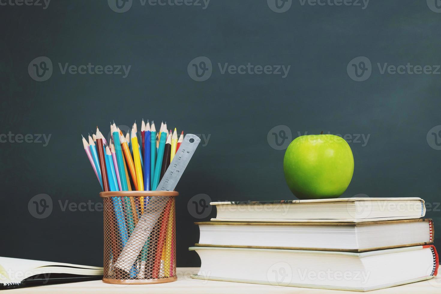 briefpapier benodigdheden en accessoires, wekker, kleur krijt, gum, krijt, potlood, puntenslijper, pen, appelrood, boek, zet op het bureau briefpapier schoolbord achtergrond. onderwijs terug naar school concept foto