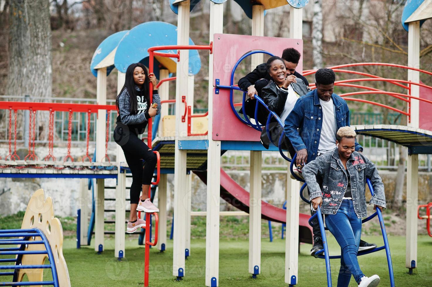 jonge millennials Afrikaanse vrienden op speelplaats, glijbaan en schommel. gelukkige zwarte mensen die samen plezier hebben. generatie z vriendschapsconcept. foto