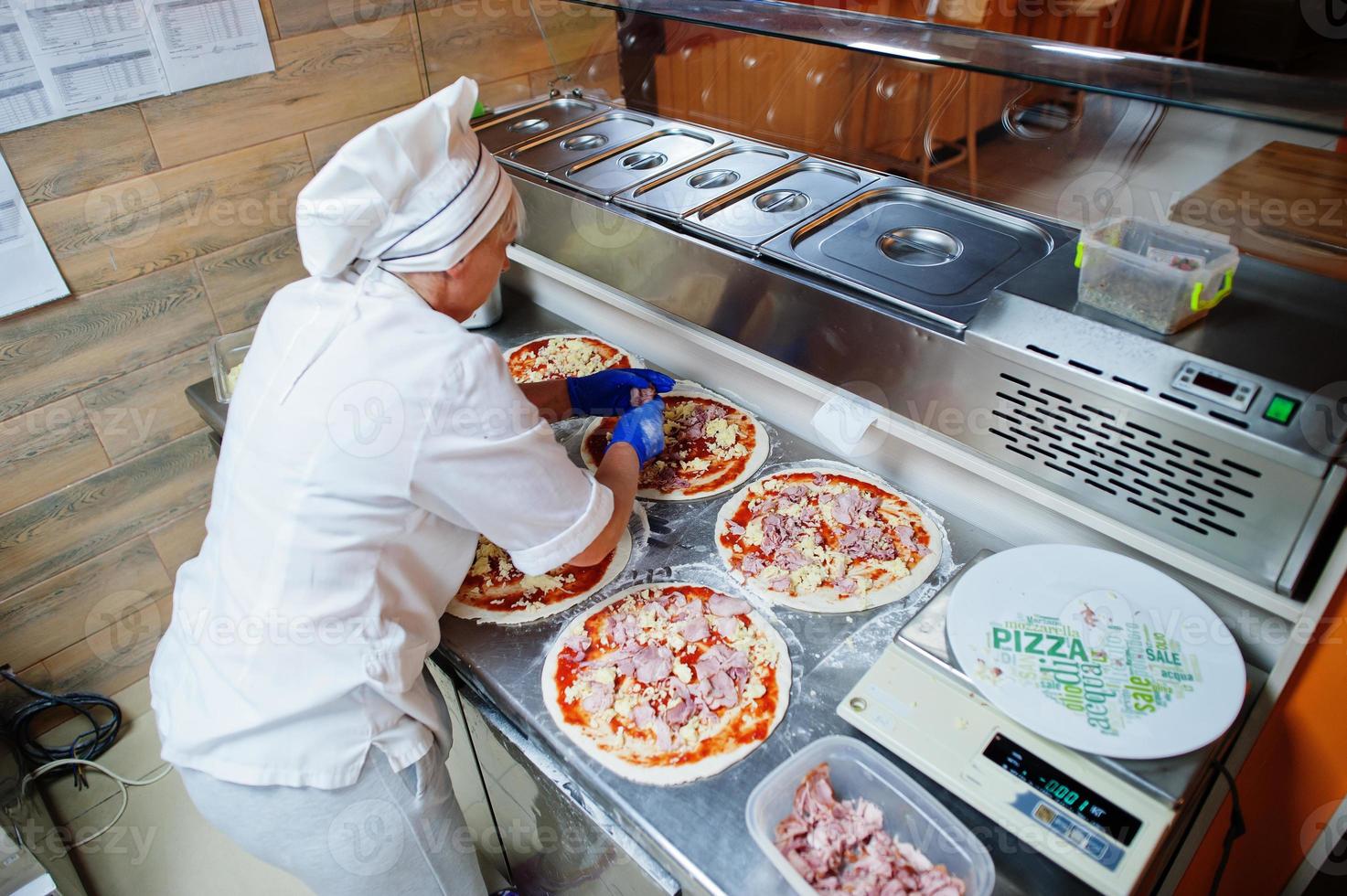 vrouwelijke chef-kok die pizza in restaurantkeuken voorbereidt. foto