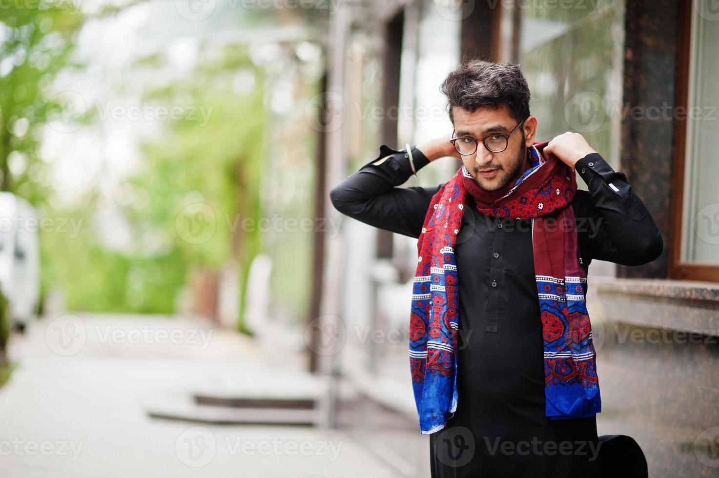 pakistaans bangladesh man draagt zwarte traditionele kleding en een bril poseert buiten. foto