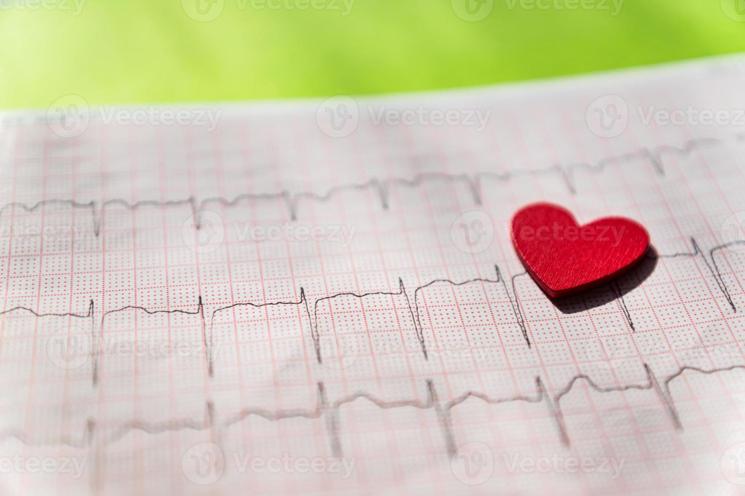 close-up van een elektrocardiogram in papieren vorm met rood houten hart. ecg- of ekg-papier op zwarte achtergrond. medisch en gezondheidszorgconcept. foto