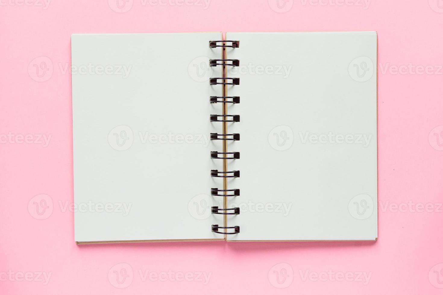 schoon spiraalvormig notitieboek voor notities en berichten op pastelroze achtergrond. minimaal zakelijk plat leggen foto
