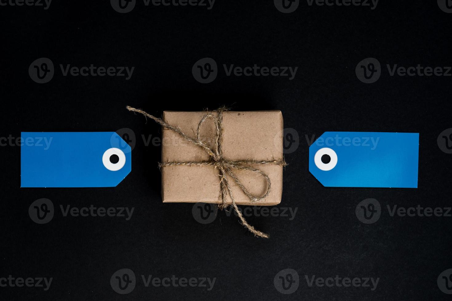 handgemaakte geschenkdoos verpakt in ambachtelijk papier met blauwe papieren kaartlabels voor decoratie. foto