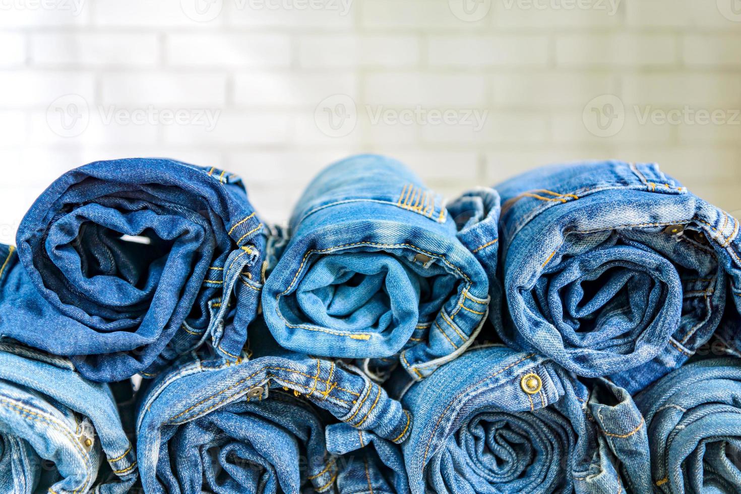 roll blue denim jeans gerangschikt in stapel op muur achtergrond. beauty en mode kleding concept foto