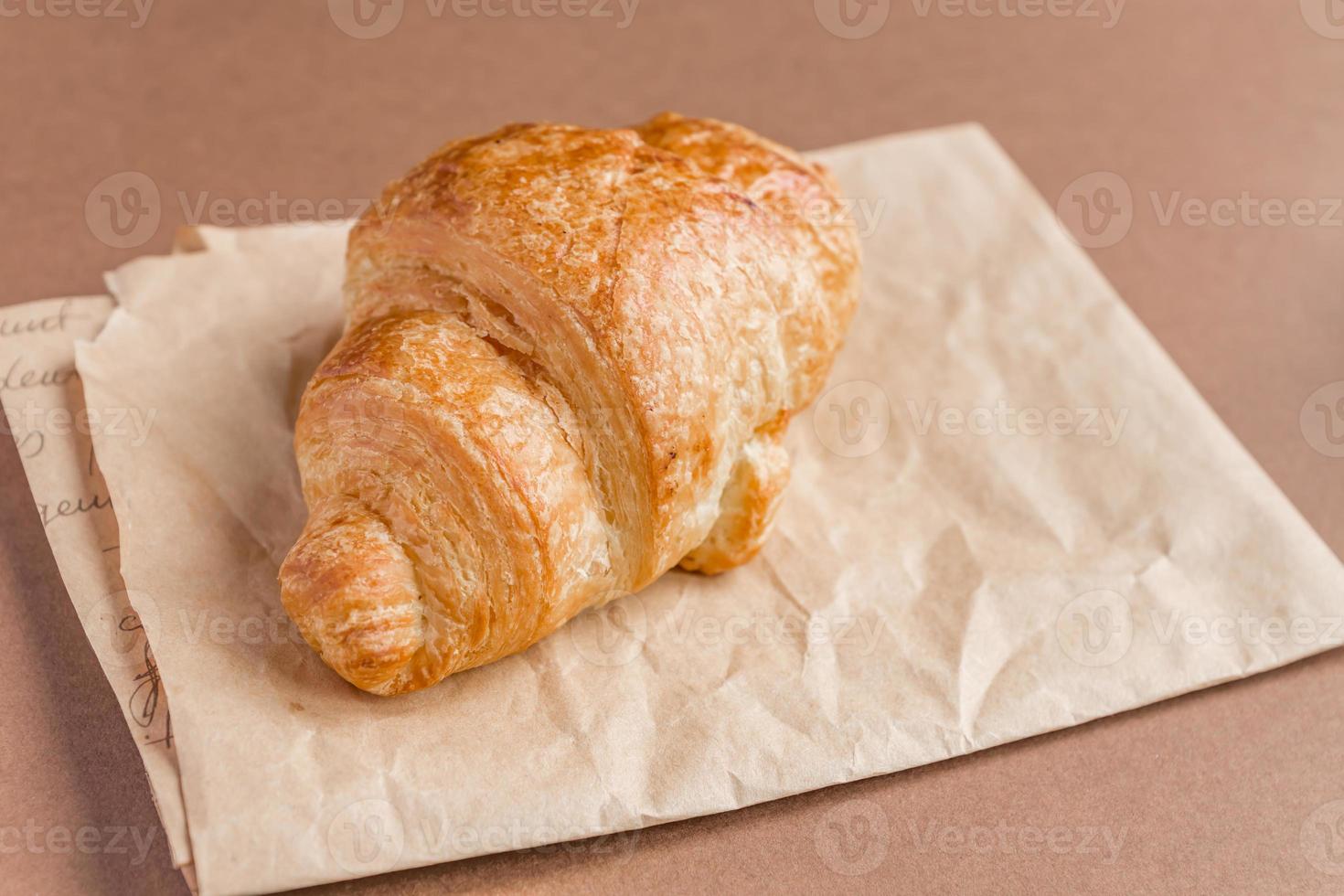 close-up van versgebakken Franse croissants op ambachtelijk papier voor het ontbijt. foto