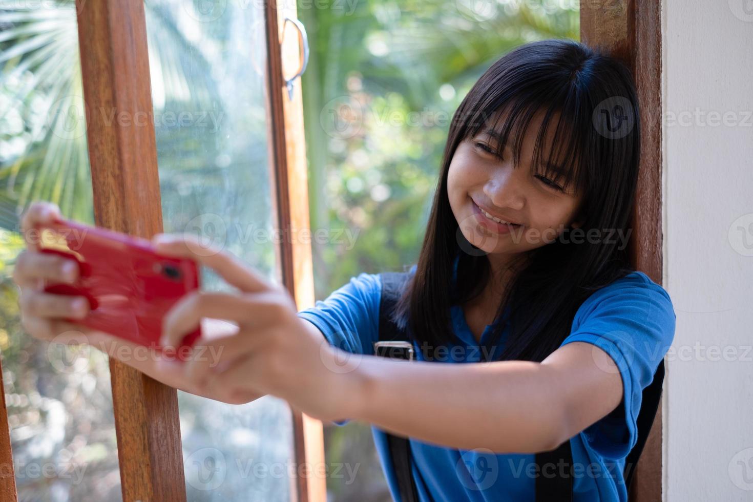 gelukkig jong meisje gebruik makend van mobiel telefoon en zittend Aan de ramen Bij huis. foto