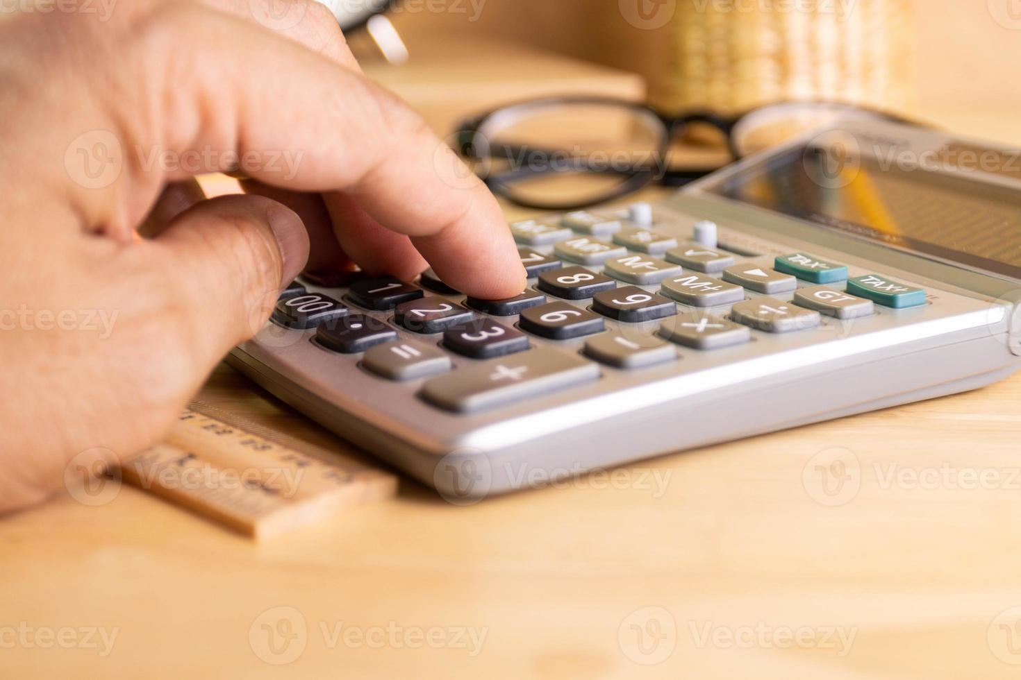 dichtbij omhoog menselijk vinger Duwen aantal knop van rekenmachine concept berekening van inkomen, uitgaven, berekening foto