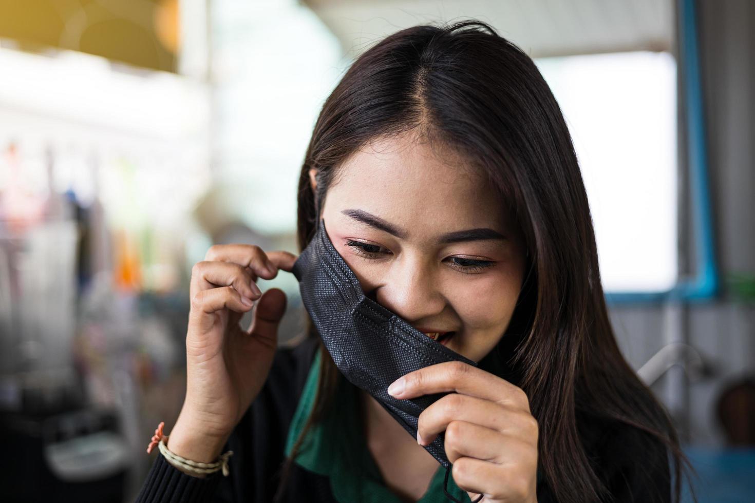 nemen een detailopname portret van een mooi Thais vrouw over naar nemen uit een zwart masker. foto