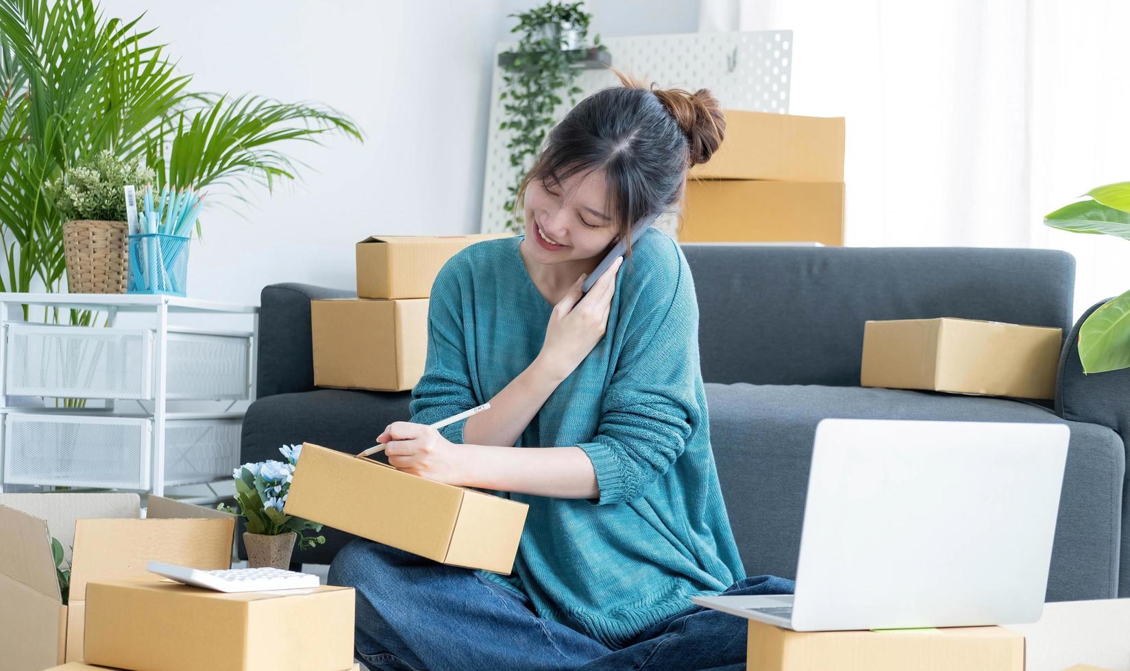 startend klein bedrijf mkb, ondernemer eigenaar die smartphone of tablet gebruikt om online aankooporder te ontvangen en te controleren om de verpakking van het pakket klaar te maken. het verkopen van online ideeënconcept foto