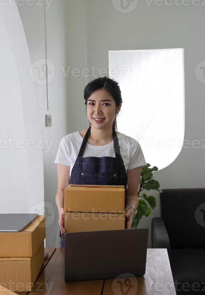 portret van aziatische jonge vrouw mkb werkend met een doos thuis de werkplek. start-up kleine ondernemer, kleine ondernemer mkb of freelance bedrijf online en leveringsconcept. foto