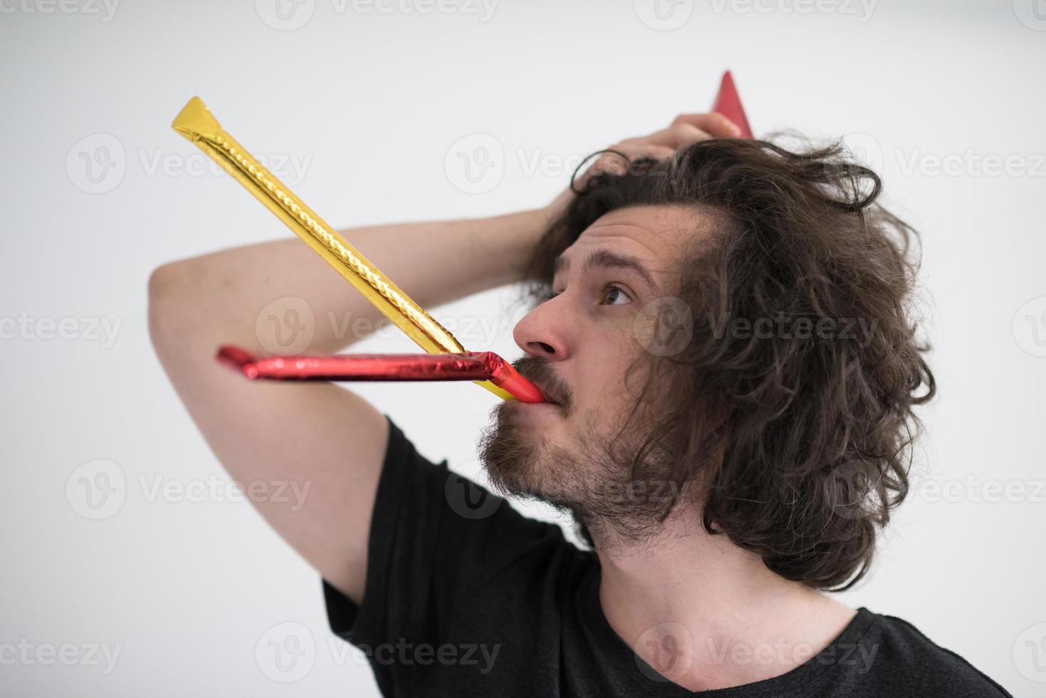portret van een man met een feestmuts die op een fluitje blaast foto