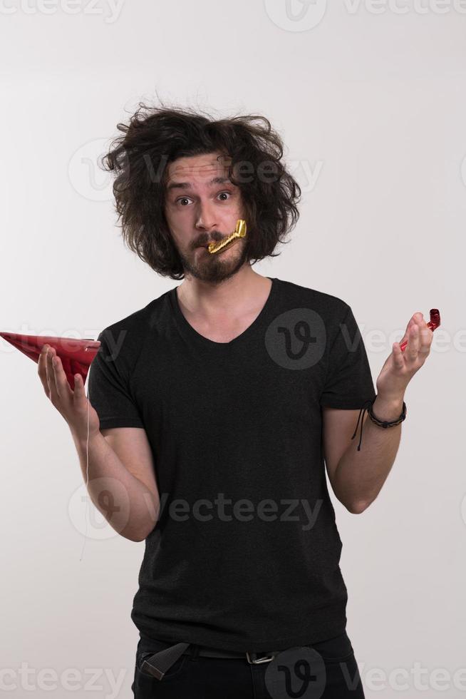 portret van een man met een feestmuts die op een fluitje blaast foto