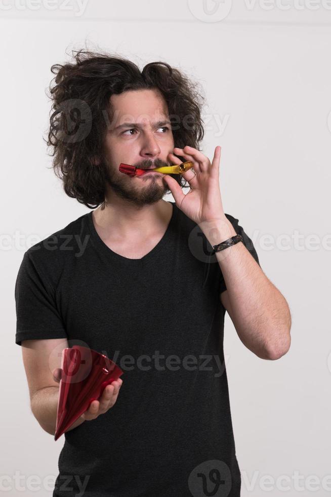 portret van een man met een feestmuts die op een fluitje blaast foto